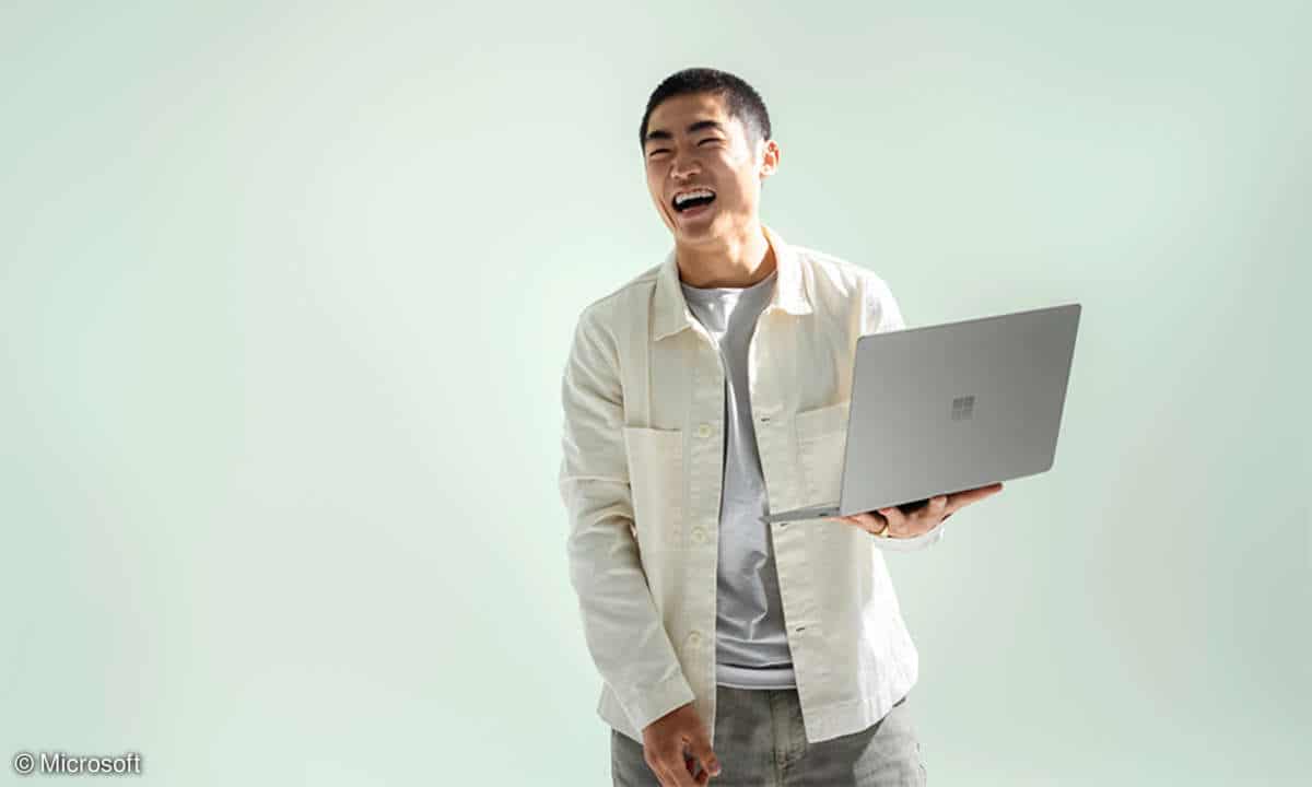 Man holding Microsoft Surface Laptop Go 2 and laughing
