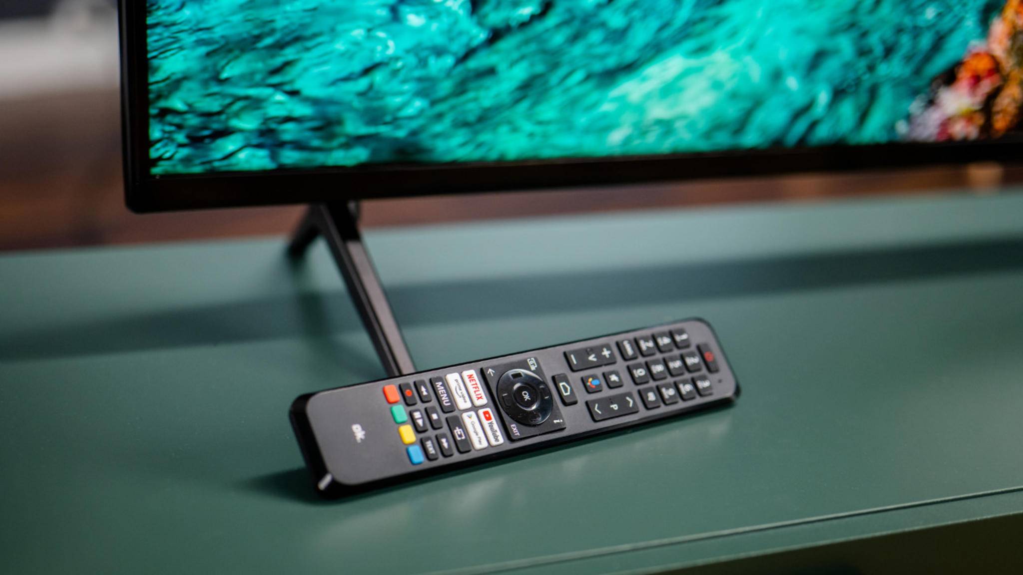 Remote control leaning on the base of a TV.