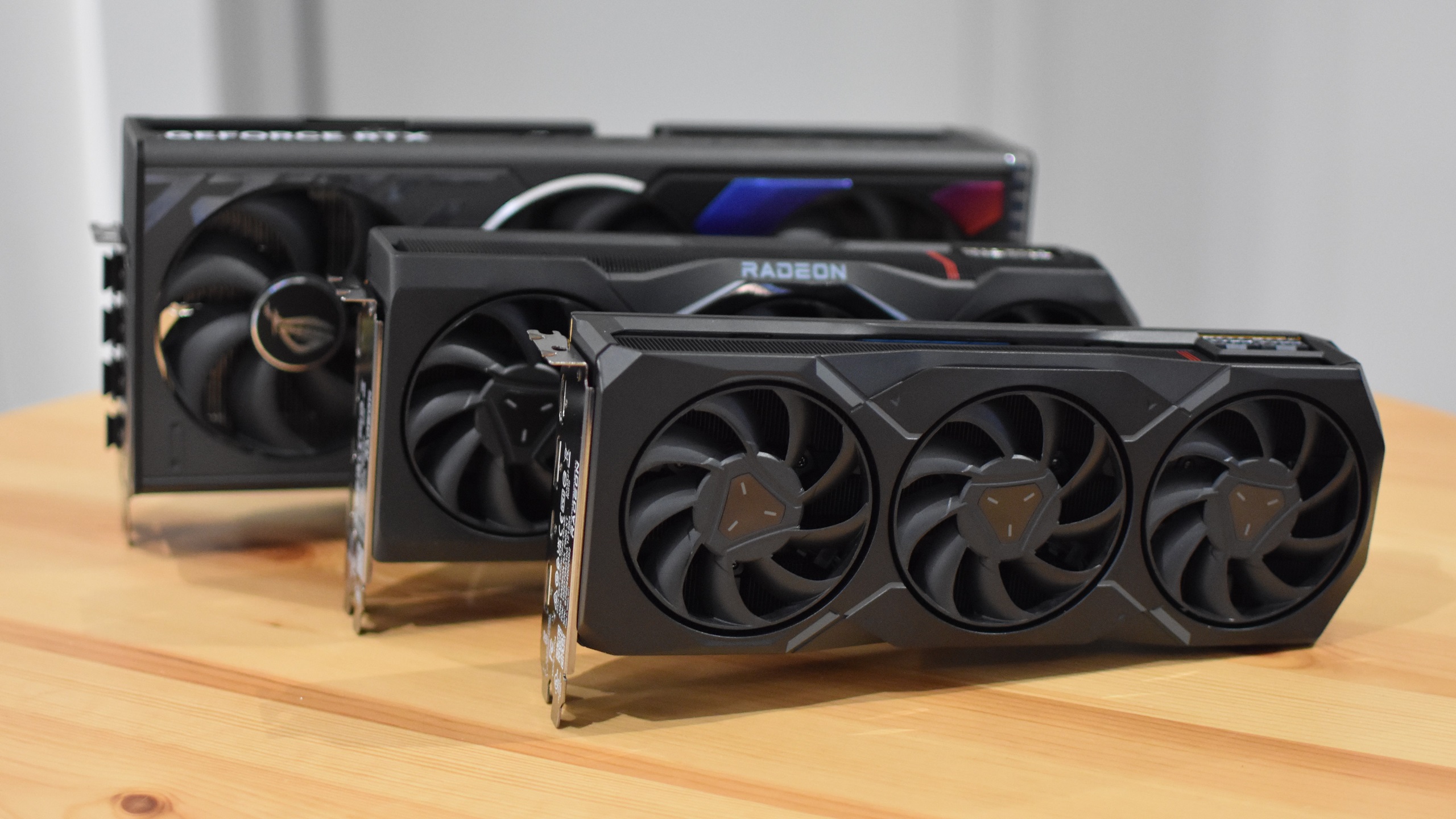 The AMD Radeon RX 7900 XT and Radeon RX 7900 XTX graphics cards laid out in front of a much larger RTX 4080.